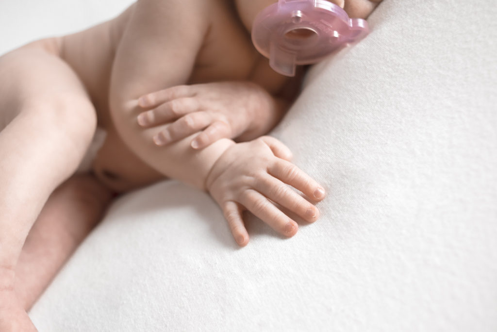 A caucasian newborn baby laying on a blanket. The photo is focused on the babies hands, showing the tiny details of the fingers. The photograph was taken at a photography studio near Johnson City, Tennesseee.
